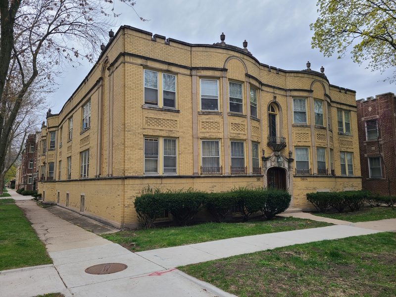 Yellow brick corner apartment building with ornamental parapet